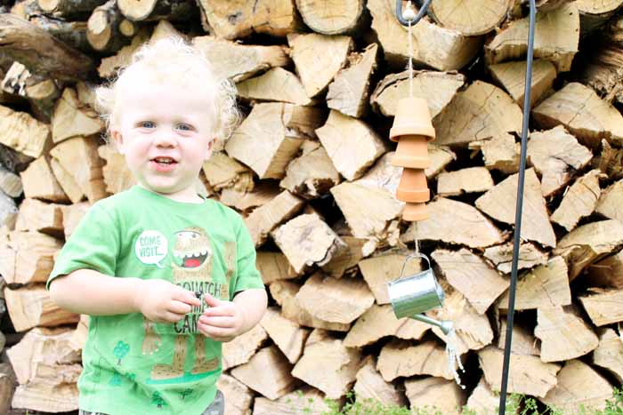 toddler stand next to homemade wind chimes 