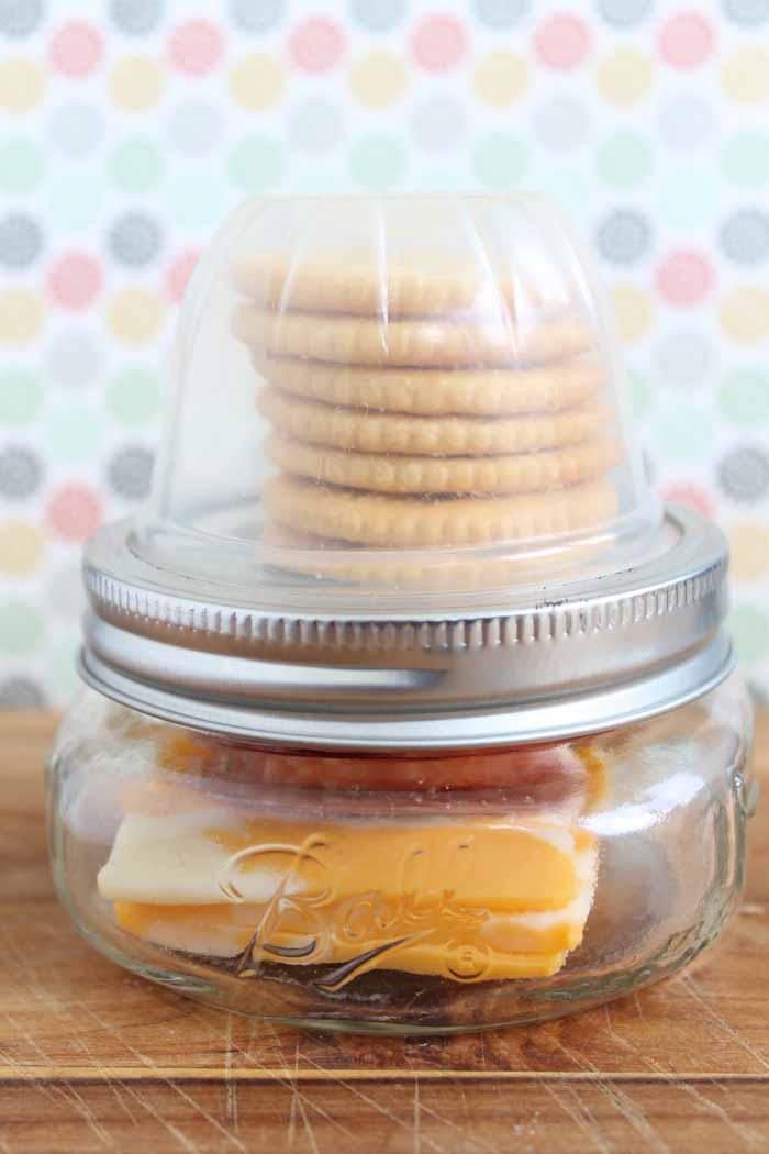 homemade lunchable with cheese, meat, and crackers on wooden table