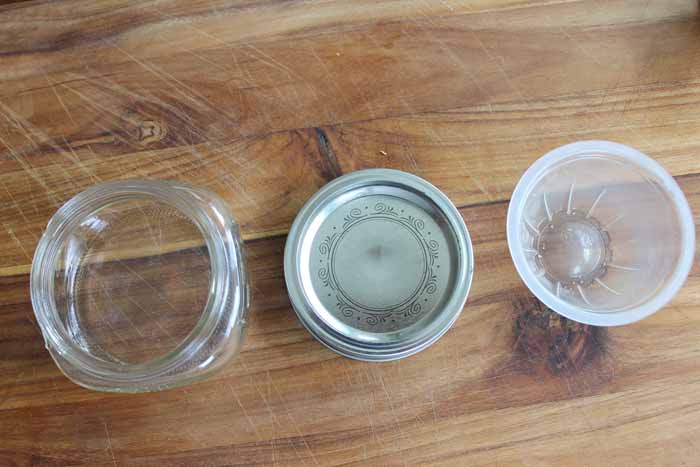 top shot of open mason jar next to lid and empty fruit cup