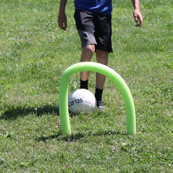 Kid getting ready to kick a soccer ball through a pool noodle goal