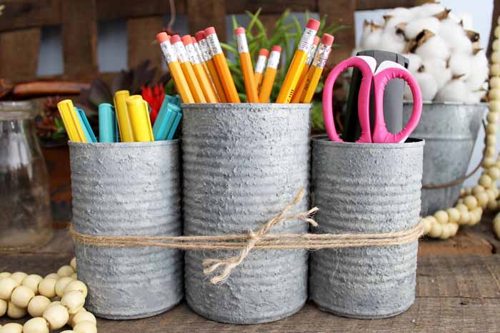 three cans tied together with pencils, markers and scissors