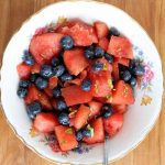 watermelon and basil salad in a white bowl on a wooden backdrop