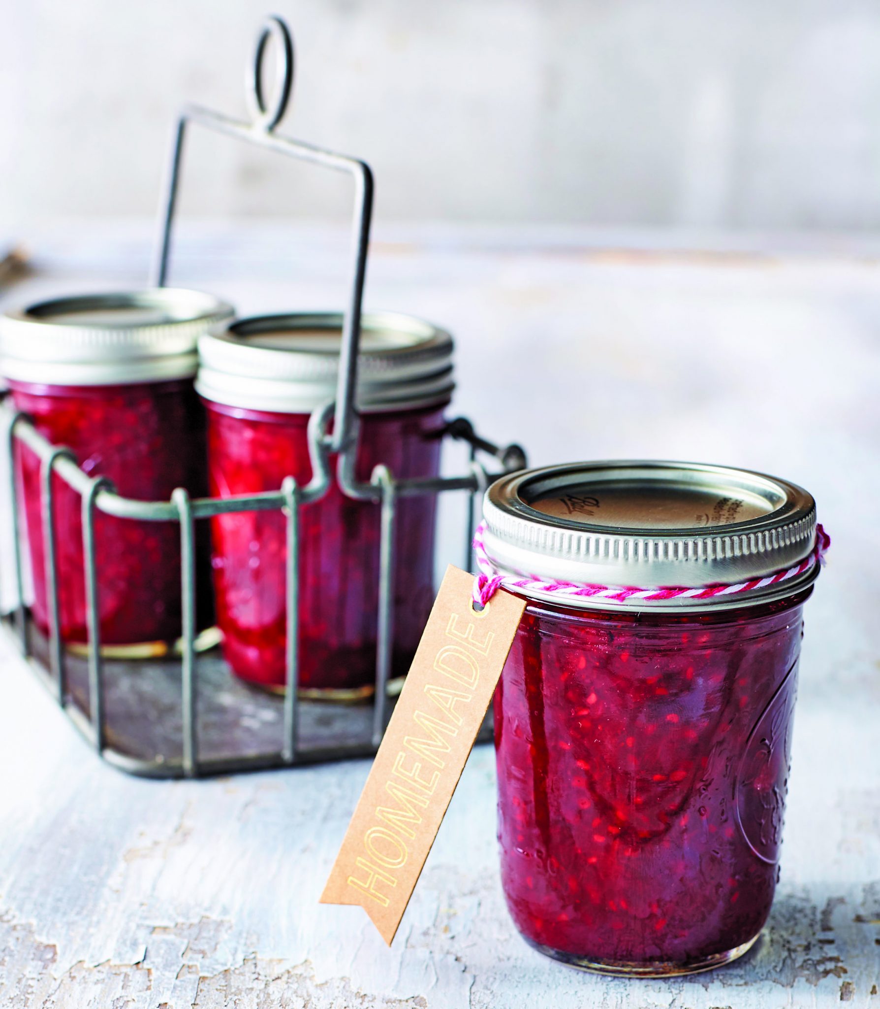 Three mason jars filled with mixed berry jam on a table