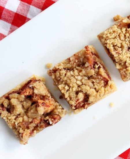 three apple bars on a white plate on top of a red checkered tablecloth