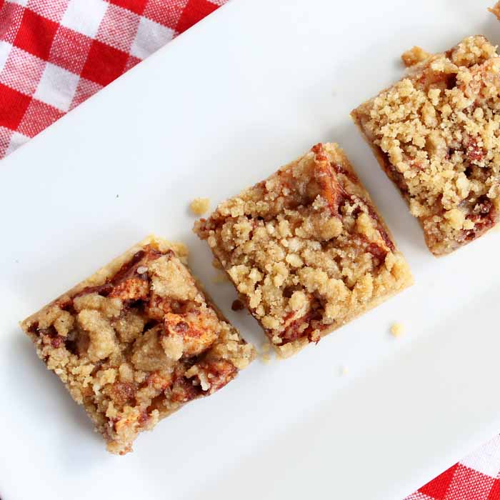 three apple bars on a white plate on top of a red checkered tablecloth
