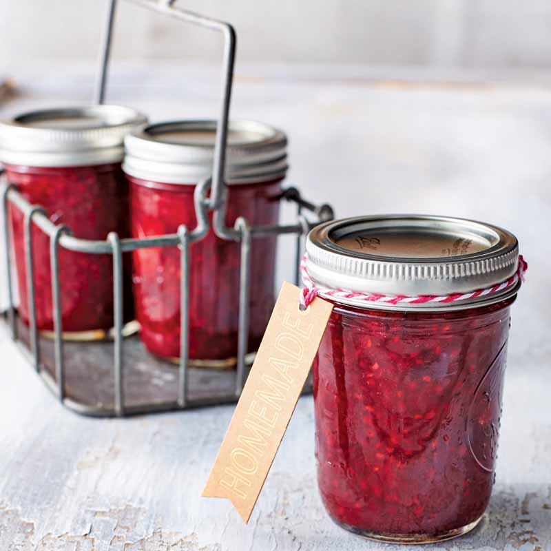 mason jar filled with red jam with a kraft paper tag
