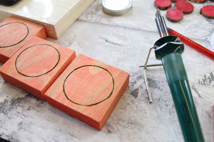 Use a wood burning tool to etch X's and O's onto the tick tac toe pieces