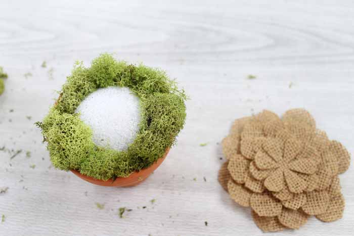 putting moss around a styrofoam ball in a terra cotta planter