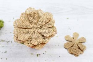 putting burlap pieces to create a flower on a whitewash wood backdrop