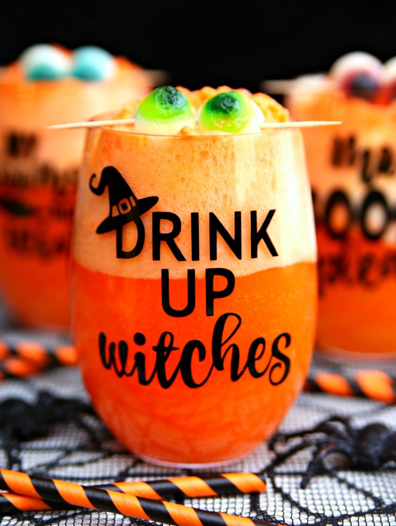 drink up witches orange drink in a stemless wine glass with monster eyeballs on a toothpick