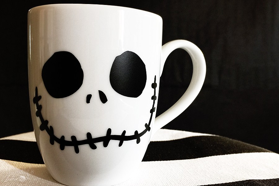 white mug with jack skellington face cut out on black striped plate
