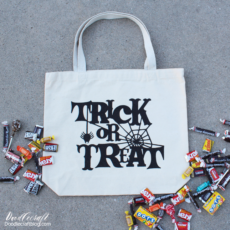 white tote bag with trick or treat letters on concrete backdrop with candy in piles