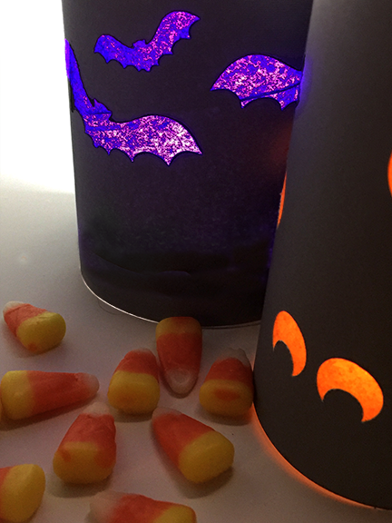 black and purple black luminary, orange eyes luminary on white with candy corn scattered