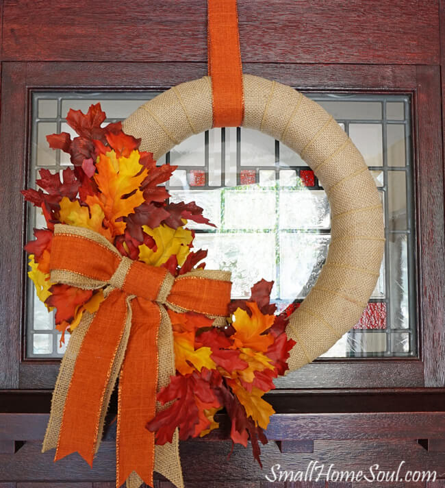 burlap wreath on front door with leaves and burlap bow