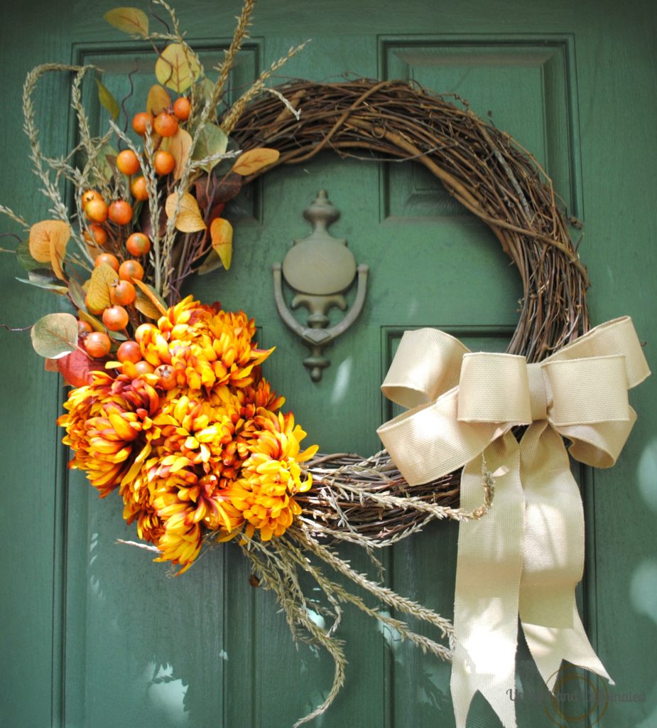 grapevine wreath with mums and burlap flower on green front door