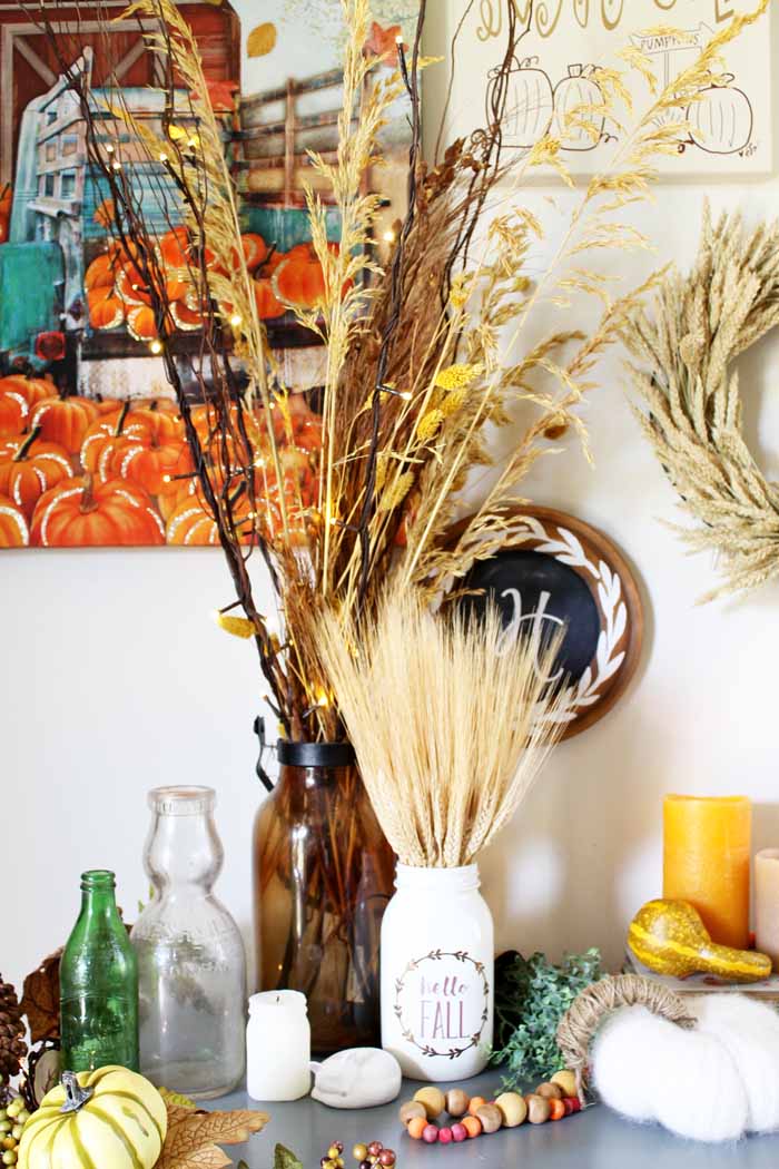 lit branches in a brown bottle with a wheat mason jar