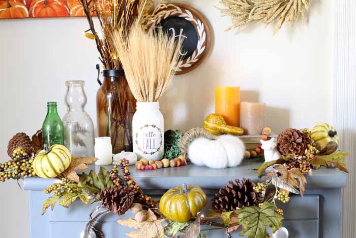 Vase of wheat on a blue table with pumpkins and garland