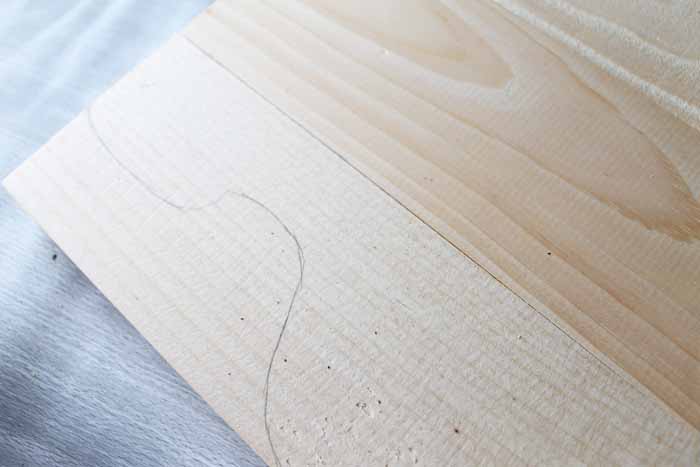 piece of wood with drawn silhouette drawn on with pencil
