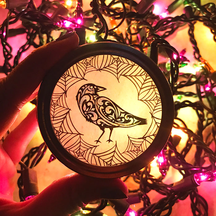 raven Cricut suncatcher on top of purple Halloween lights