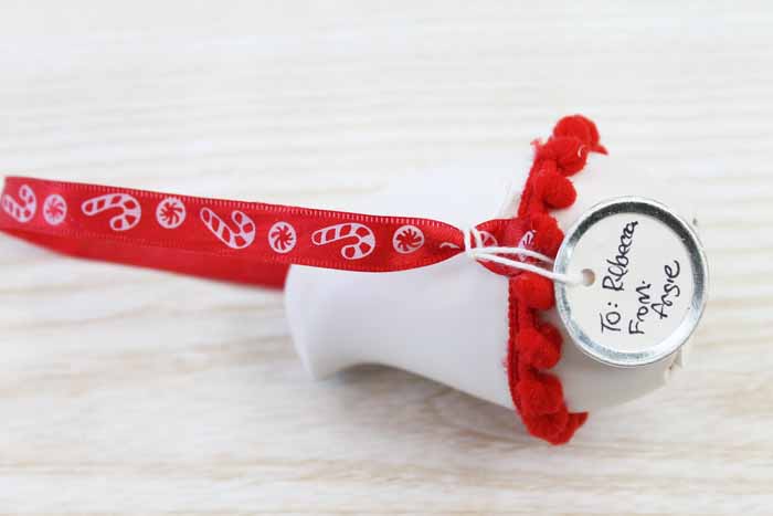 red pom pom trim on Christmas ornament; white wood backdrop