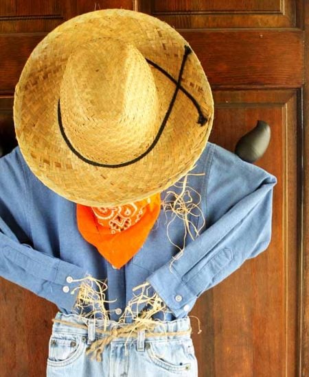 Olika holding a scarecrow wreath on a wooden front door