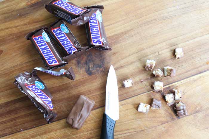 snicker candy bars wrapped and chopped snickers on a wooden cutting board