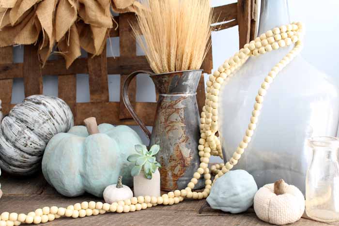 painted pumpkins, wheat and wooden beads in front of a tobacco basket