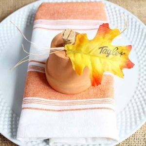 clay pot pumpkins for Thanksgiving place cards on an orange striped kitchen towel