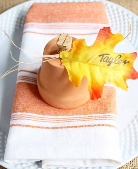 clay pot pumpkins for Thanksgiving place cards on an orange striped kitchen towel