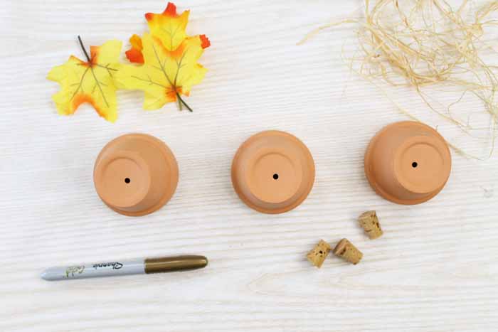 clay pots and faux leaves to make a diy placecard that looks like a pumpkin.
