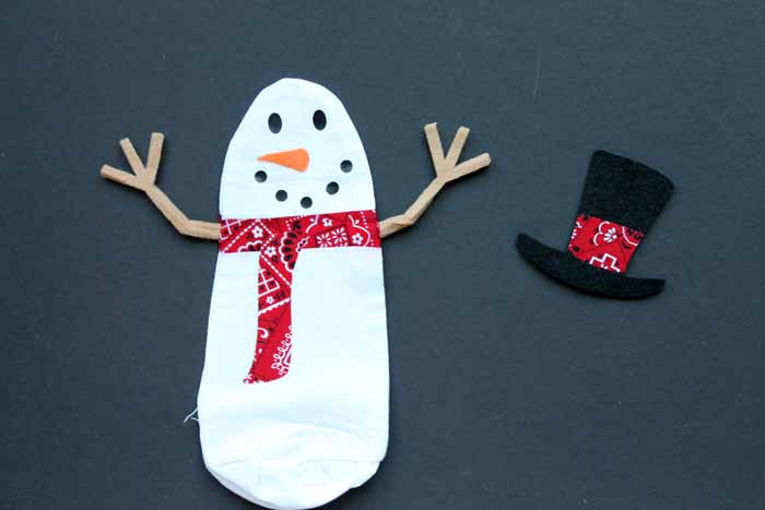 Snowman cut from a cricut with hat beside him on a black background