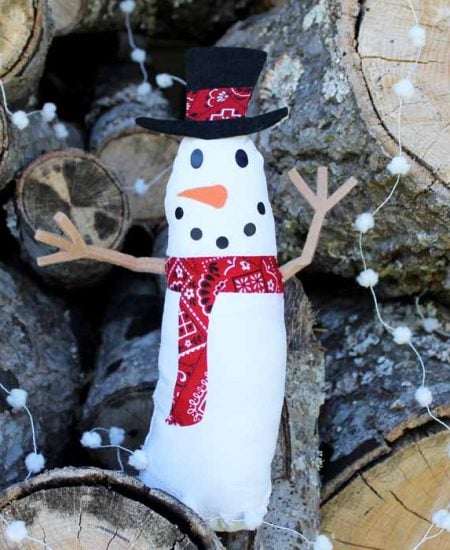 cricut snowman craft for winter in front of logs