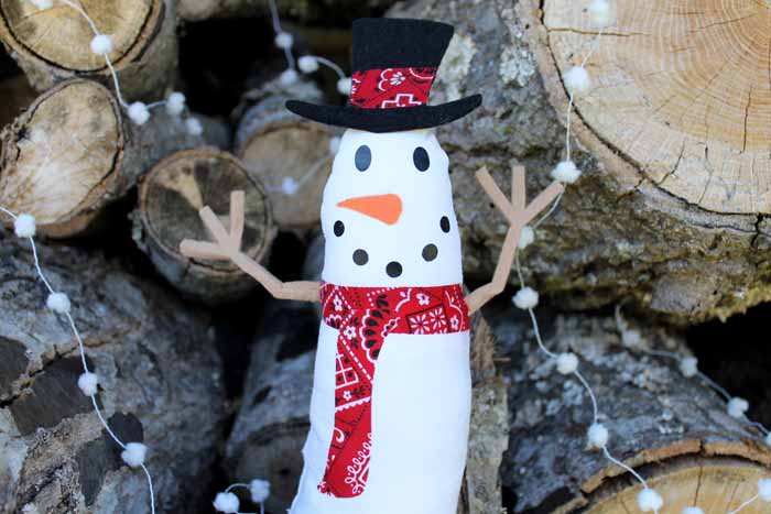 Cricut craft snowman in front of wood and pom pom garland