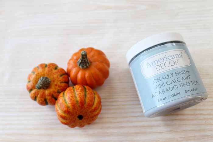 supplies used to make decorative gourds, orange plastic pumpkins and blue chalk paint 