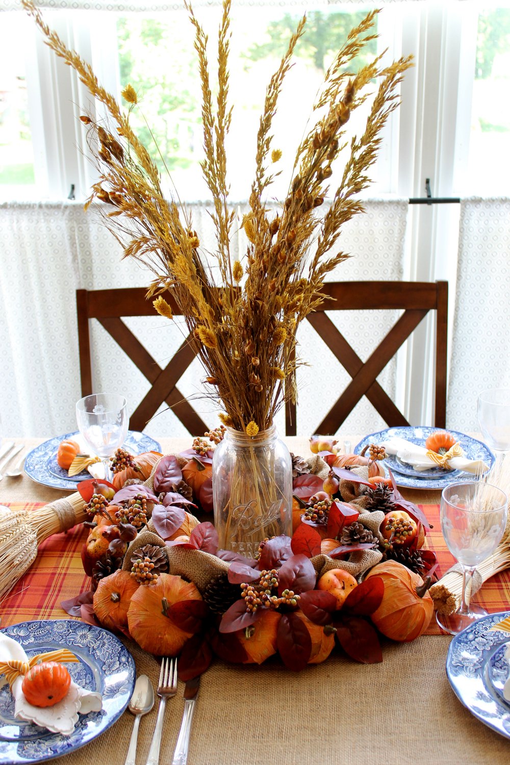 This DIY Thanksgiving table centerpiece is put together with a mason jar and simple fall foliage