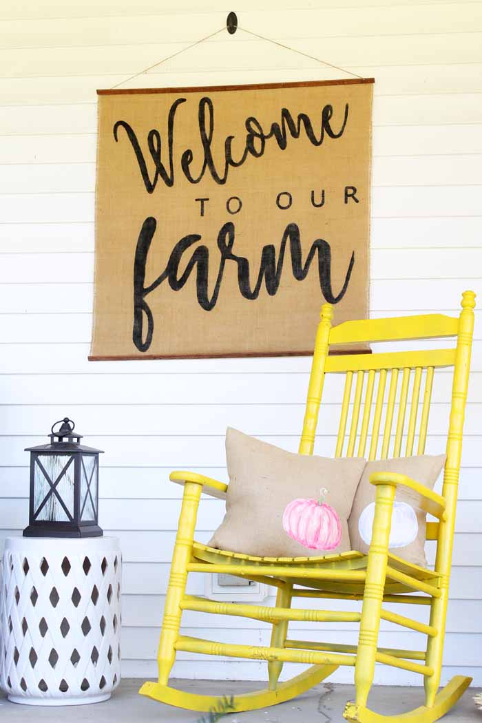 welcome to our farm sign with a yellow rocking chair with burlap pillows