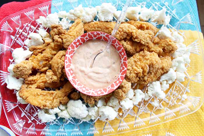ranch dip in the center of a tray surrounded by chicken and cauliflower