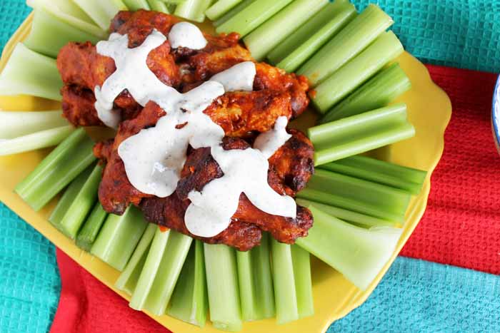 hot wings covered in ranch surrounded by celery sticks