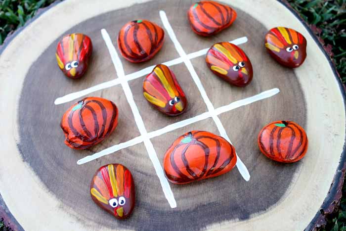 Wood slice tic tac toe game with Thanksgiving-themed painted rocks