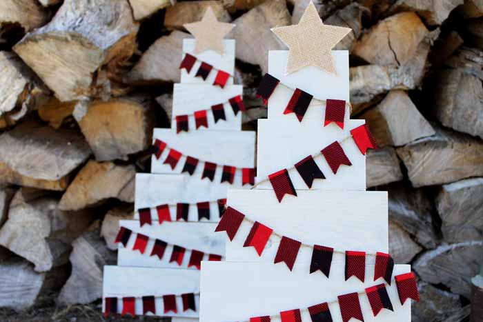 adding a burlap star on top of a pallet Christmas tree