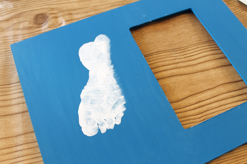 white footprint of a baby on a blue photo frame