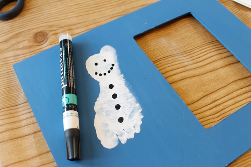Baby Footprint Art Photo Frame adding details to a snowman with a black paint pen