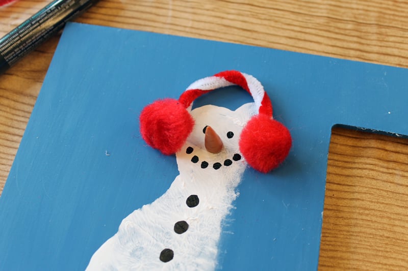 Footprint Art Photo Frame adding earmuffs to a footprint snowman
