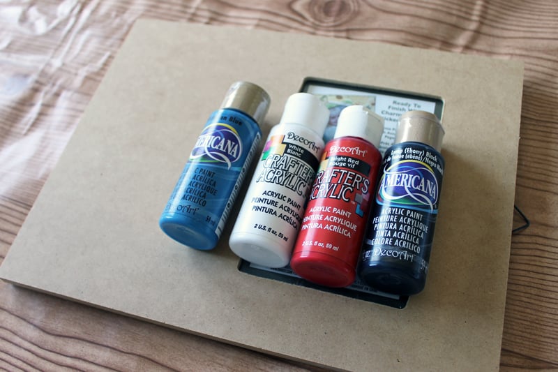 bottles of craft paint on a plain photo frame on a table