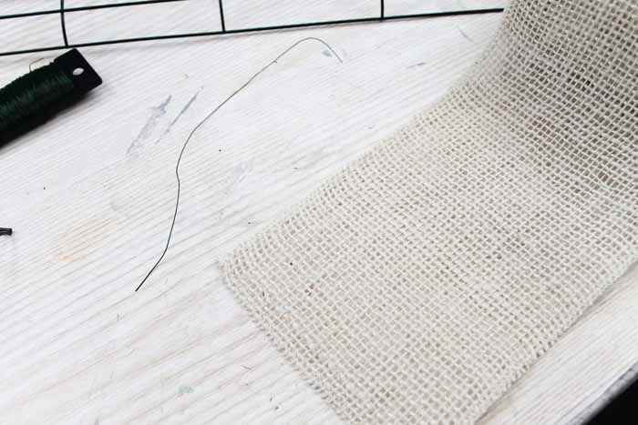 Learn how to make your own DIY candy cane wreath with these step by step instructions. Add this whimsical DIY Christmas wreath to your home! white burlap ribbon and floral ribbon