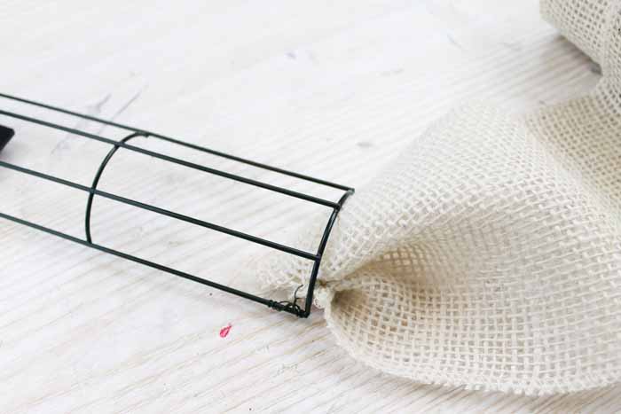 Learn how to make your own DIY candy cane wreath with these step by step instructions. Add this whimsical DIY Christmas wreath to your home! white burlap ribbon tied on wire wreath form