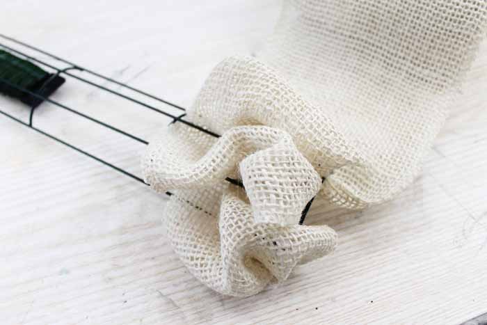 Learn how to make your own DIY candy cane wreath with these step by step instructions. Add this whimsical DIY Christmas wreath to your home! bunching burlap ribbon on a wire wreath form