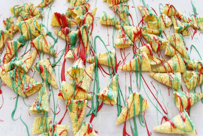bugles laying on parchment paper covered in red and green melting chocolate 