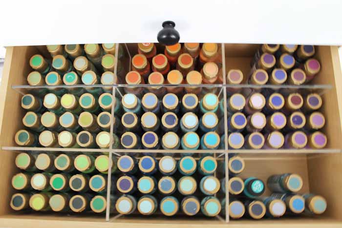 bottles of craft paint standing in a drawer