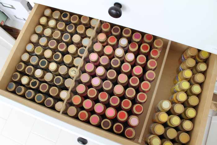 various colors of craft paint in a drawer of a closet